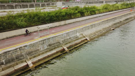 low angle drone panning right shot over a river next to busy asian roads