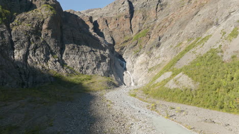 first-person view moving toward small waterfall flowing between mountain rocks of lyngen fjord, norway