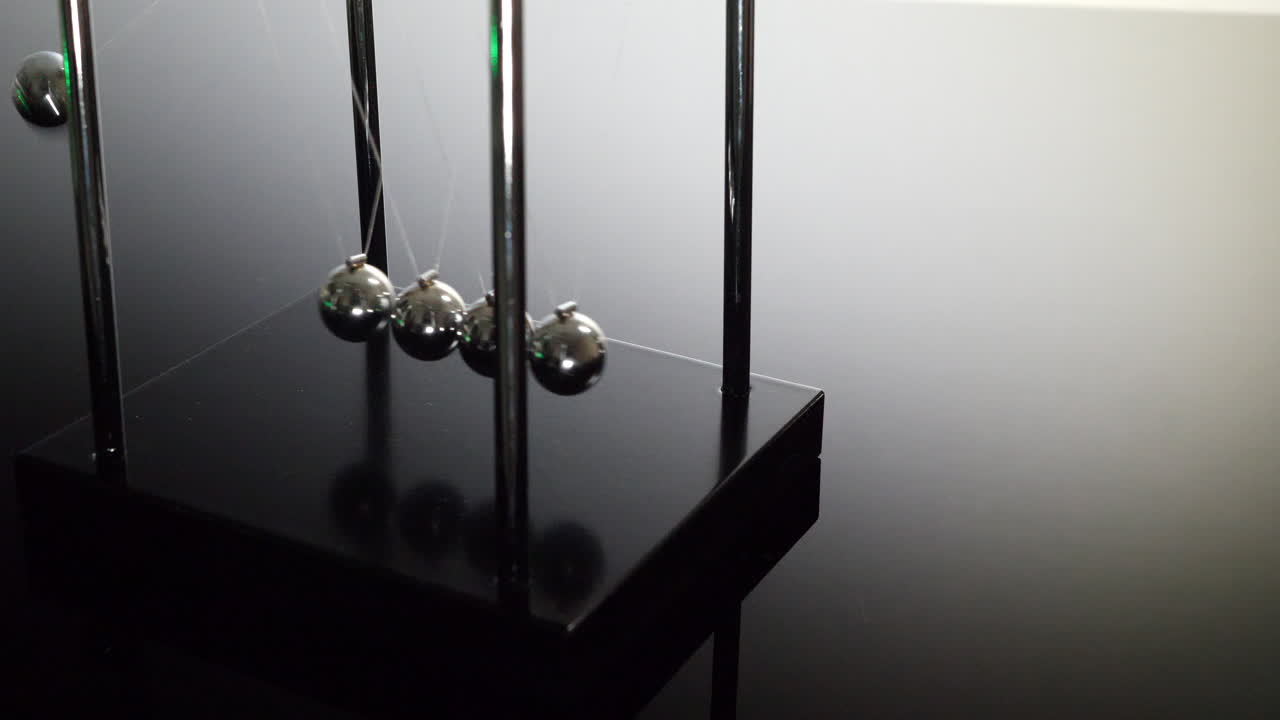 흑백 배경에서 물리학 법칙과 운동량 보존 원리를 보여주는 뉴턴 요람