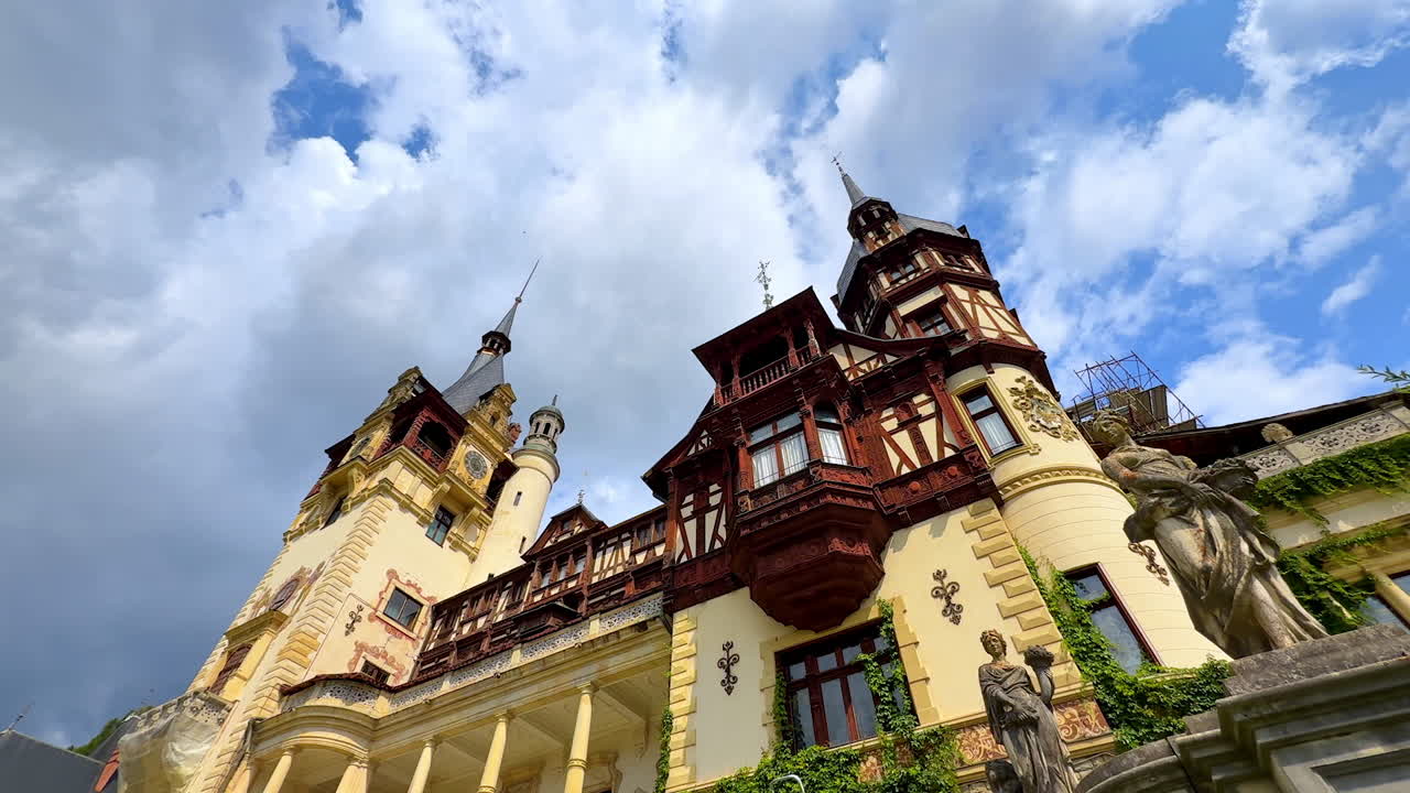 Beautiful female statues in front of the façade of Peles Castle, Prahova County, Romania. Low angle view at the stunning architecture against cloudy sky