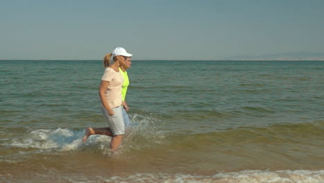 Pareja-Joven-Corriendo-En-Aguas-Poco-Profundas-Del-Mar