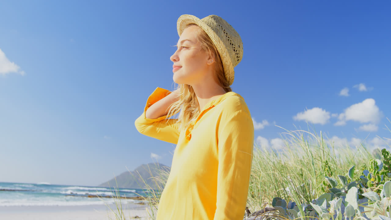 해변에 서 있는 젊은 백인 여성의 측면 뷰 4k