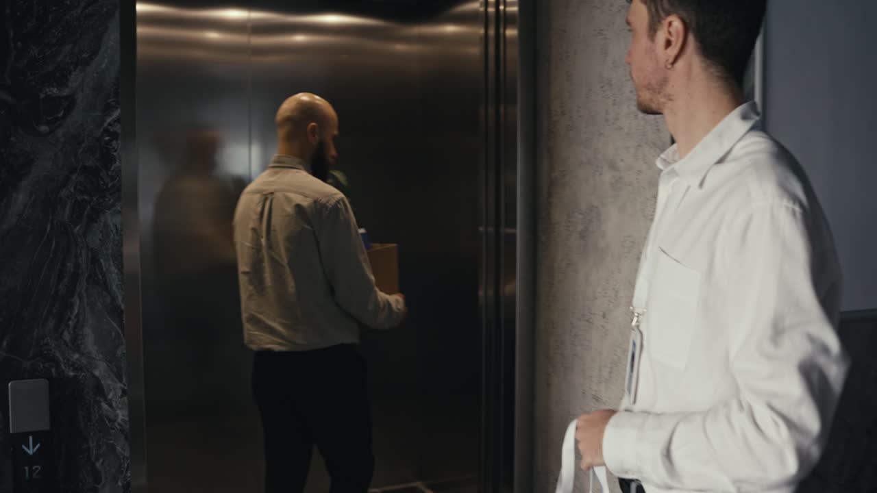 Two men in an office building near an elevator