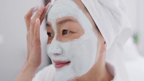 video of happy asian woman in robe with moisturizing mask