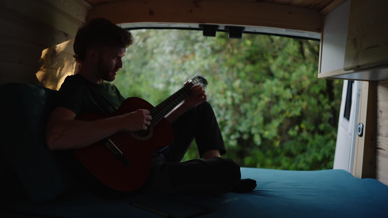 Uomo che suona la chitarra in un camper