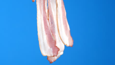 men's hand holds the bacon slices.