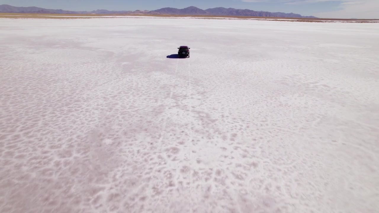 Car Exploring the Vast Expanse of a Stunning Salt Flat - tilt up reveal