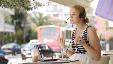 mujer riendo con auriculares en un café al aire libre