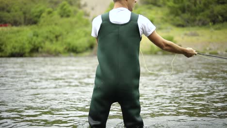 Toma-En-Cámara-Lenta-De-Un-Pescador-Caucásico-Lanzando-Su-Anzuelo-Mientras-Pesca-Con-Mosca