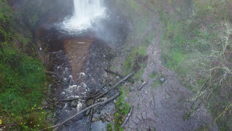 disparo de drone aéreo de arriba hacia abajo inclinándose hacia arriba para revelar una cascada con árboles cortados y camino 4k