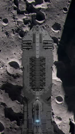 vertical shot of top down aerial view of the moon as a large futuristic spaceship passes over the surface