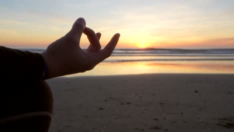 Mantra-Mit-Der-Hand-Einer-Frau,-Die-Bei-Sonnenaufgang-Vor-Dem-Meer-Yoga-Macht