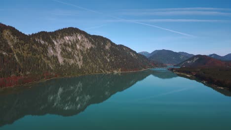 sylvenstein speicher in autumn, idyllic mountain valley river reservoir lake with fresh blue water in bavaria austria alps, flowing down a beautiful forest along trees near walchensee