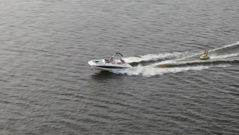 Powerboat-Pulling-Small-Boat,-Cruising-Across-The-Sea-At-Daytime