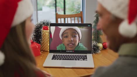 Glücklicher-Kaukasischer-älterer-Mann-Und-Enkelin-Bei-Einem-Videoanruf-Mit-Einem-Jungen-Zur-Weihnachtszeit