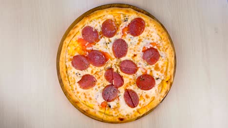 pizza de salami en una tabla de madera en la mesa.
