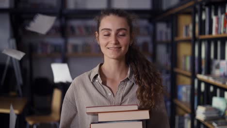 girl holding a lot of books in the library, paper sheets falling around her