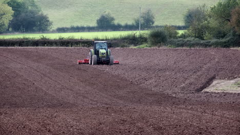 A-farmer-driving-a-tractor-tilling-and-raking-a-ploughed-field-during-autumn-in-the-Worcestershire-Countryside,-England