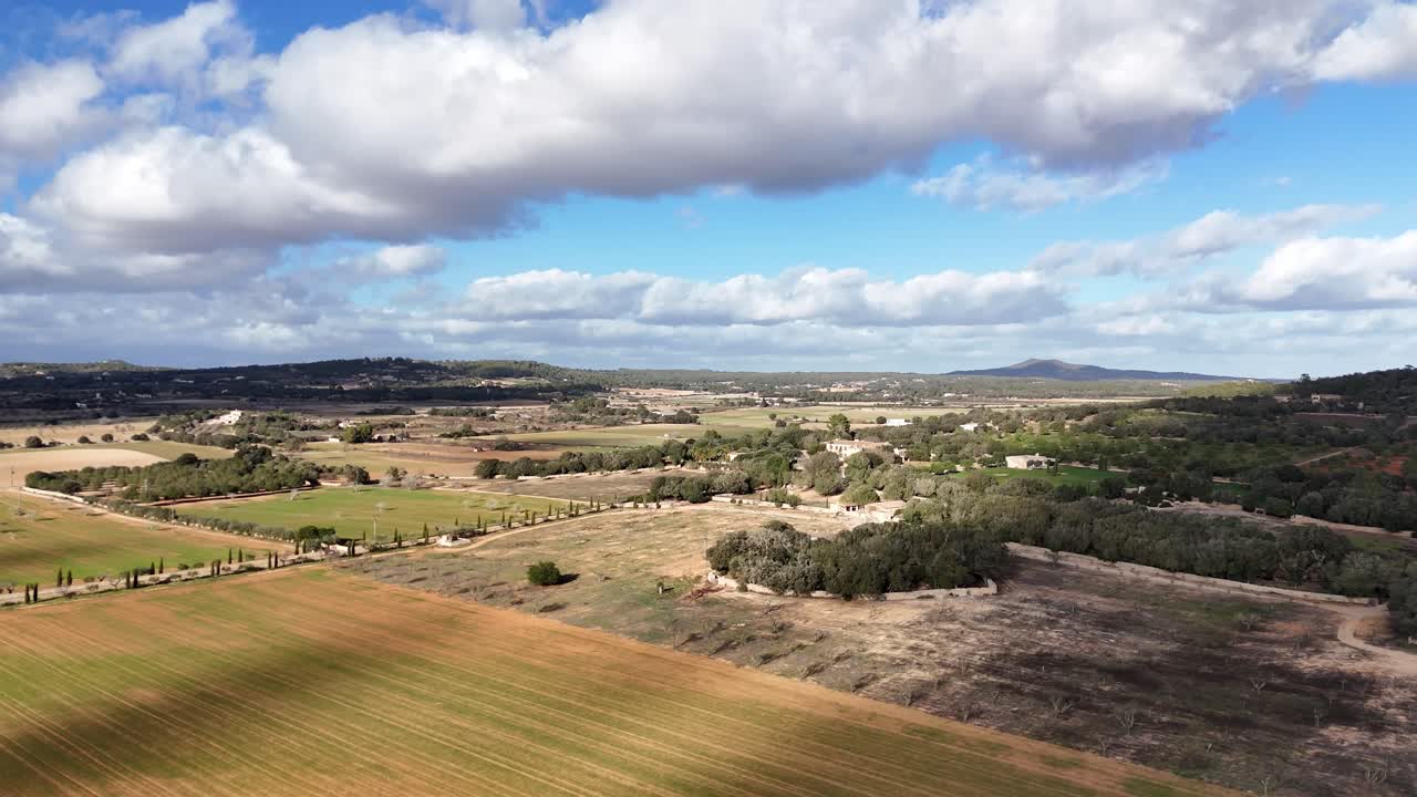 tomada amplia de un dron que muestra campos agrícolas de la isla de mallorca durante un día soleado con nubes en el cielo
