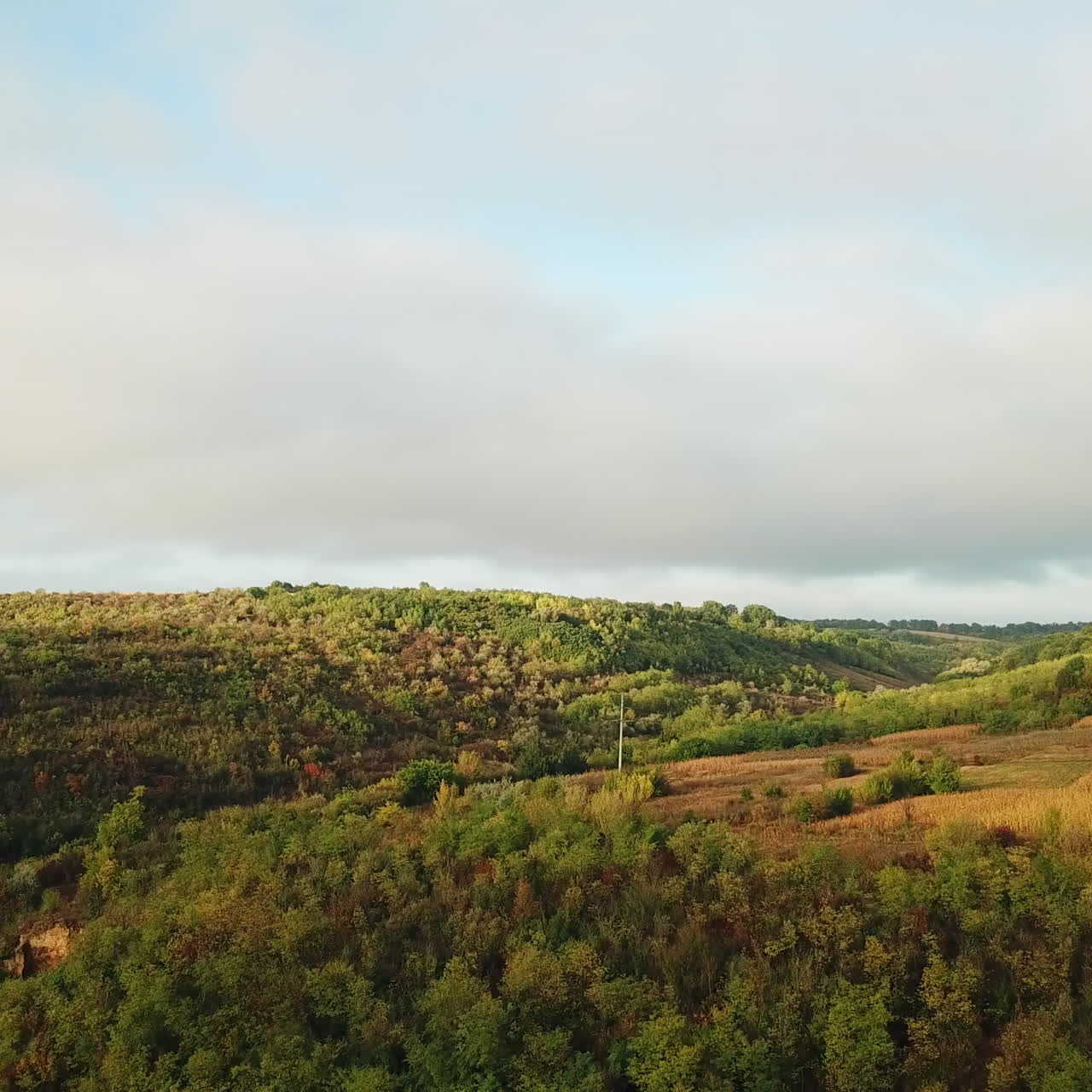 Beautiful landscape of rural place with brown meadows and fields. Panorama of natural environment with hills and forests under the sky. Slow motion of camera