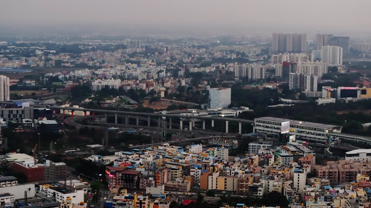 Pemandangan udara lanskap kota elektronik dengan gedung-gedung, jalan layang, jalur metro, kabut, dan kendaraan bergerak di Bangalore, Karnataka, India. Siang hari, bidikan dorong masuk, bidikan drone, 4K