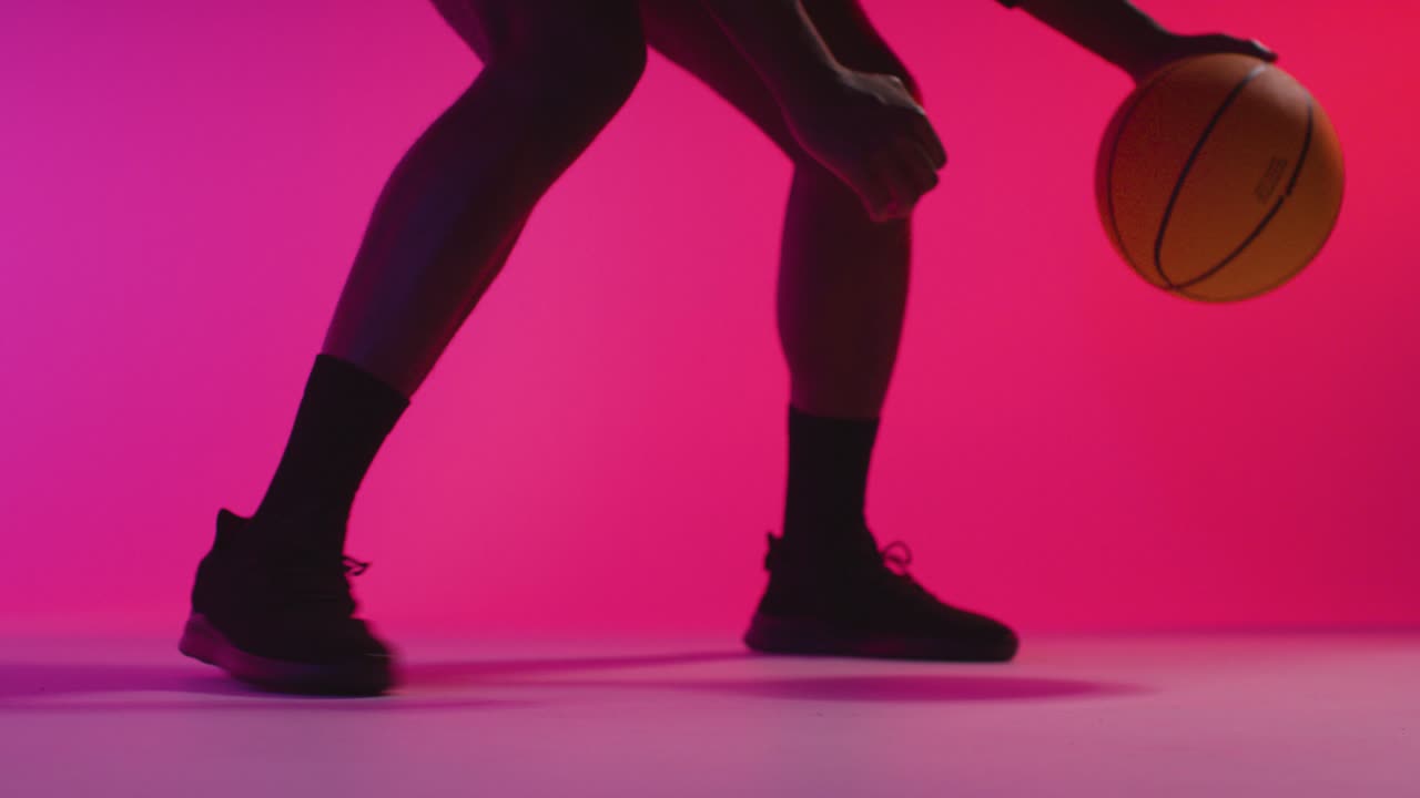 retrato de estudio en primer plano de un jugador de baloncesto masculino driblando y rebotando la pelota contra un fondo iluminado de color rosa 6