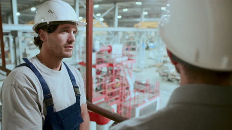 técnico discutiendo operaciones de fábrica con ingeniero industrial