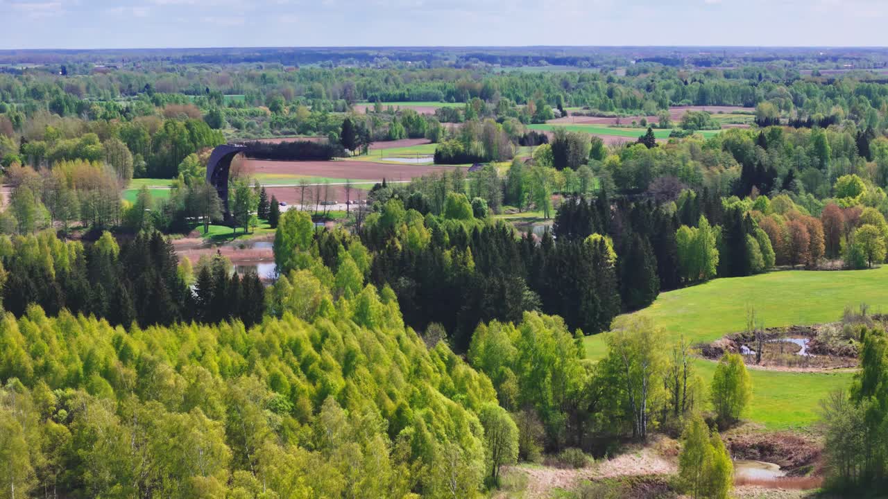 Overlooking Scenic Karst Lakes and Lush Green Countryside, the Kirkilai Observation Tower Stands Tall in Biržai Regional Park, Lithuania - Aerial Drone Shot