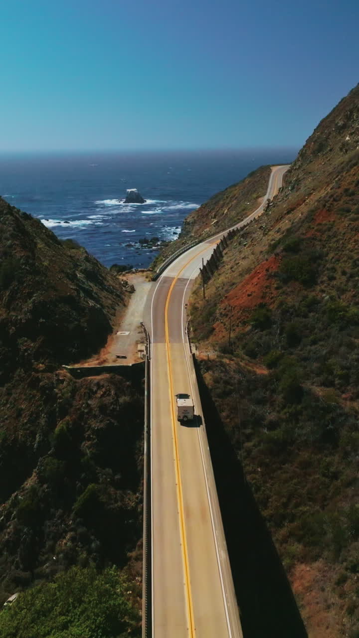 Following the truck riding by the dangerous mountainous highway of California on sunny day. Amazing blue ocean opening to the view. Vertical video