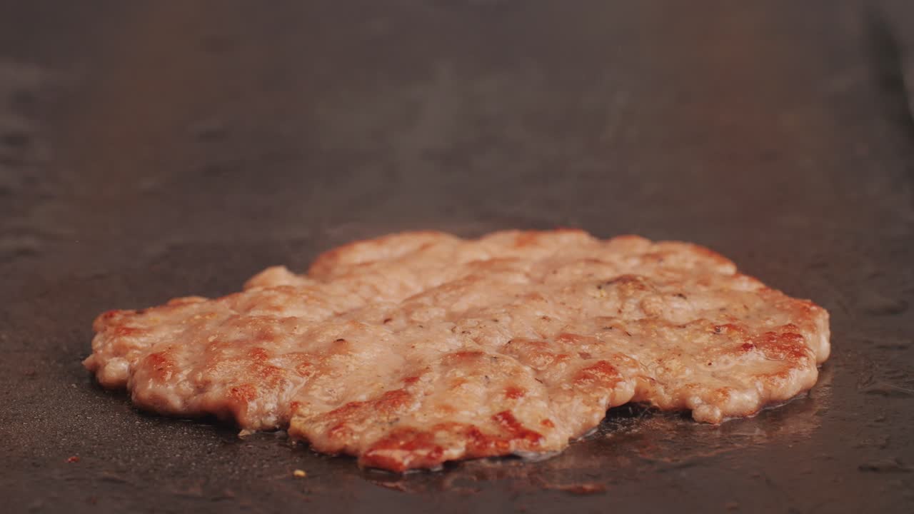 Cooking American fat smash burger on grill close-up. Beef or pork cutlet smashing by burger press. The chef in kitchen of the restaurant making cutlets for burgers - smash burger beefsteak. Fast and street food concept. High quality 4k footage