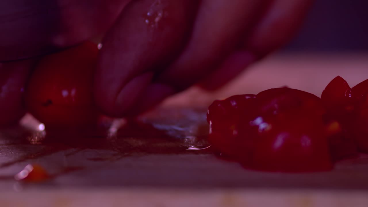 Cutting red little tomatoes in half slice on wood board,close up slow motion