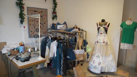 a vintage sewing workshop with handmade garments, sewing machines, and displayed accessories