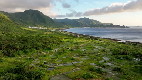 aerial flyover agricultural cultivation fields and coastline of orchid island with ocean in sunset