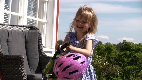 happy smiling little girl takes helmet to ride a bicycle