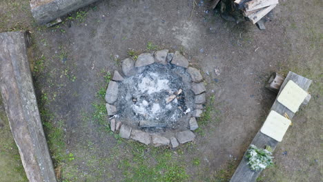 burnt-out camping fireplace with ashes encircled by benches in czechia
