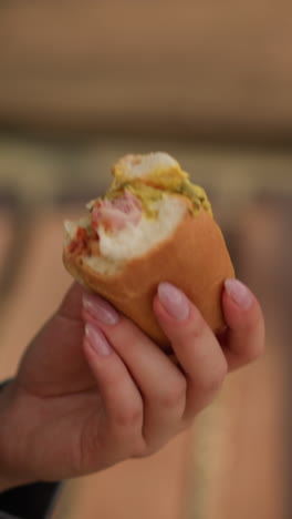 toma de primer plano de alguien tomando un bocado de shawarma, centrándose en la mano y el momento de comer, con un fondo borroso