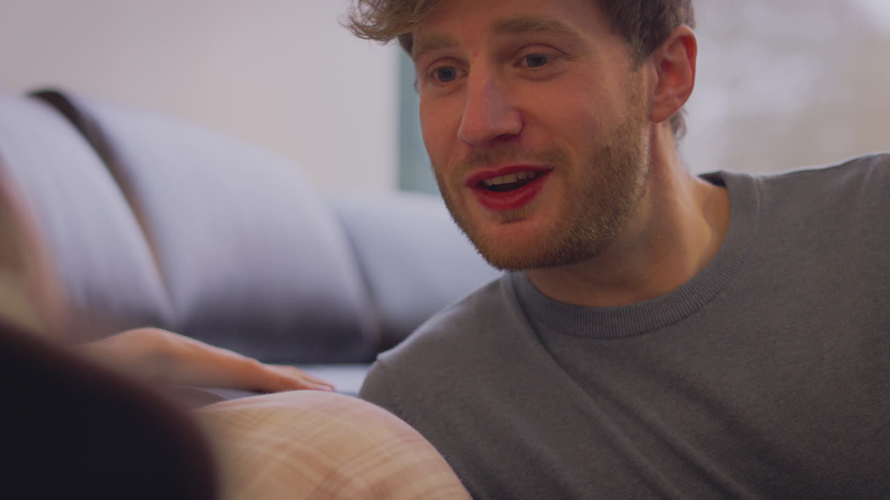 Loving Couple With Man Holding Hand Of Pregnant Partner With Prosthetic Arm At Home