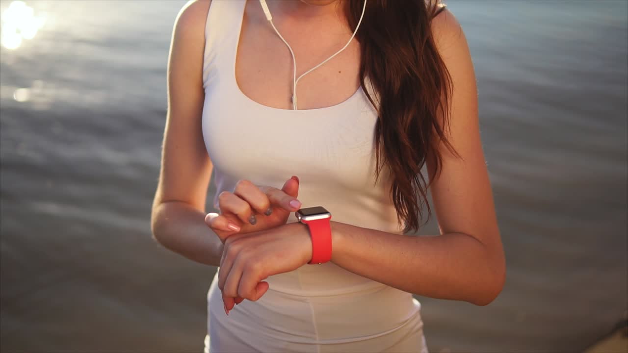 Woman Checking Fitness Tracker on Beach