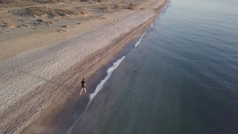Young athlete runner man with fit strong body training on beautiful sunset at beach