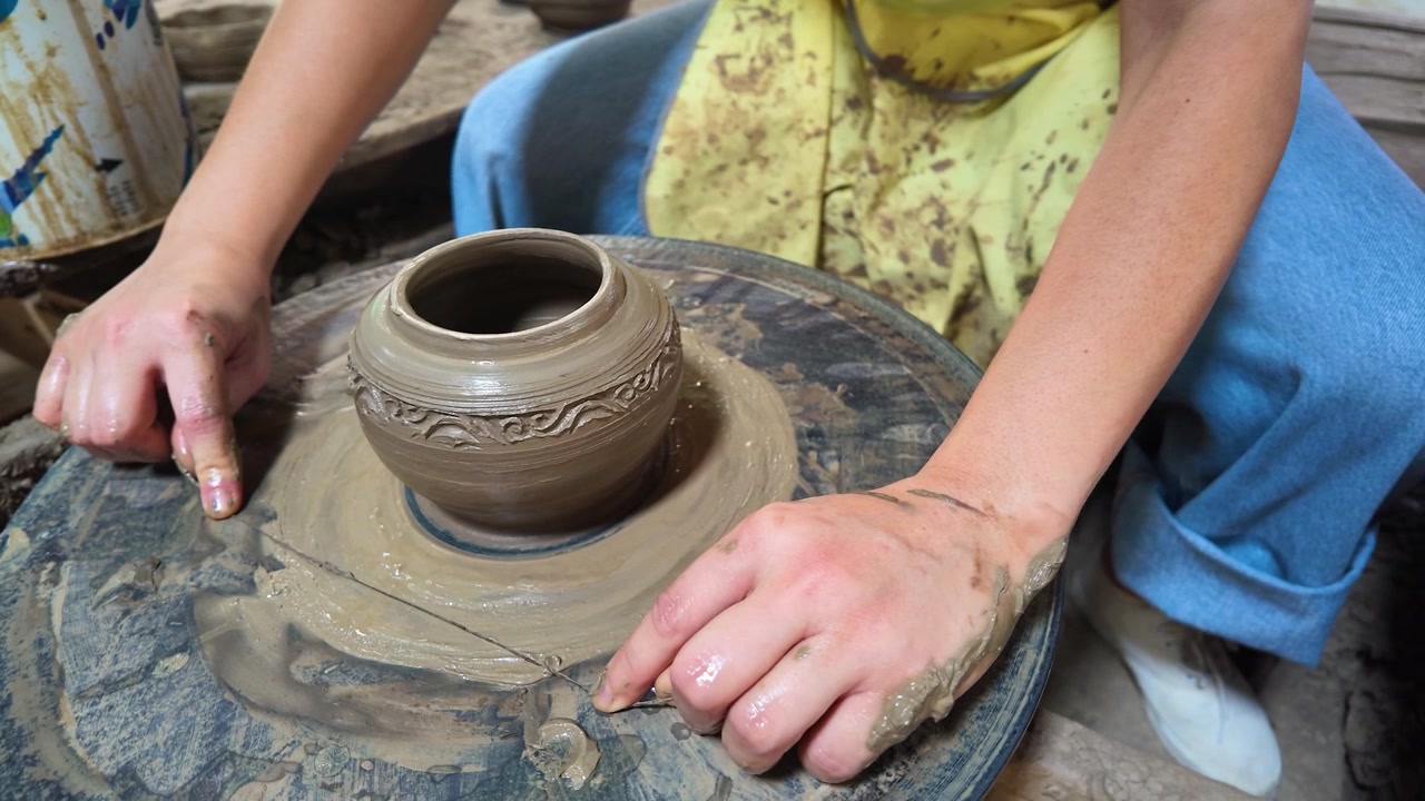Primo piano di mani che modellano un vaso di argilla su un tornio manuale a Nonthaburi
