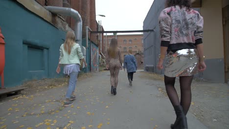 group of fashionable women walking through an urban alleyway