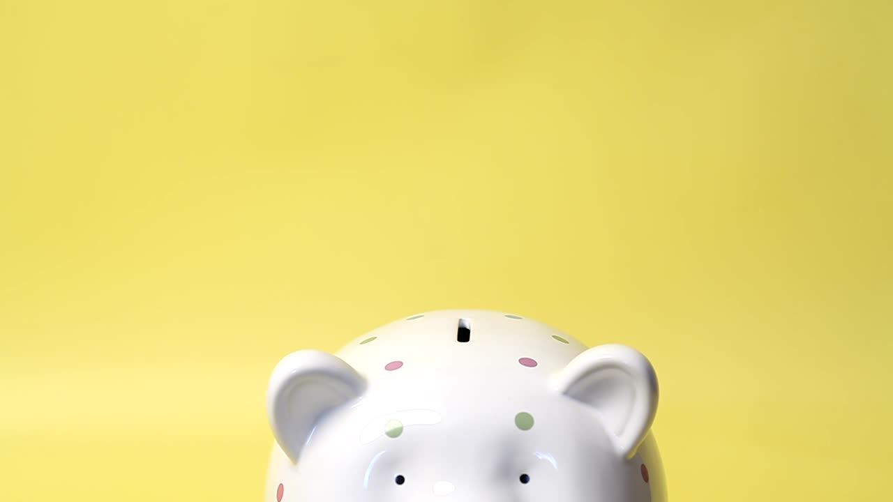 la mano pone un billete de cien dólares en una alcancía.