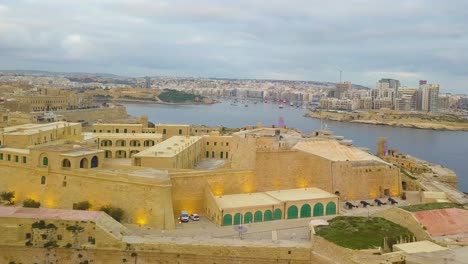 Un-Dron-Volando-A-Lo-Largo-Del-Gran-Puerto-Desde-Fort-St-Elmo-Hacia-El-Monumento-De-La-Campana-En-Los-Jardines-Barrakka-Hacia-En-Valletta-Malta