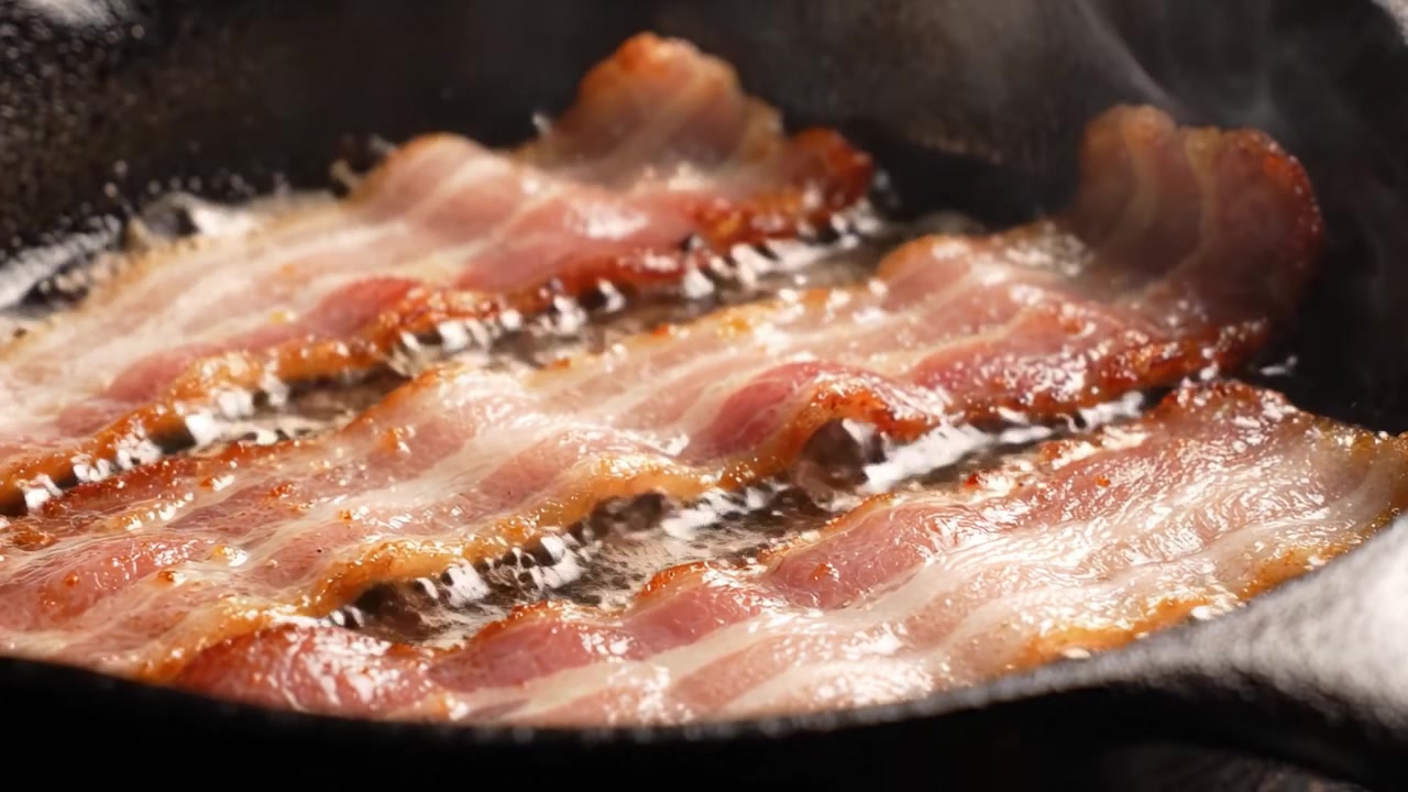 Pancetta Deliziosamente Croccante che Cuoce in una Padella di Ghisa: Una Delizia Culinaria con un Aroma Saporito e Grasso Perfettamente Sciolto per la Beatitudine della Colazione