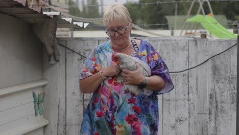 elderly woman holding a grey chicken
