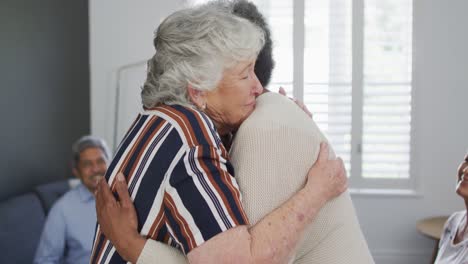 mujer mayor caucásica dando apoyo a una amiga afroamericana en una reunión