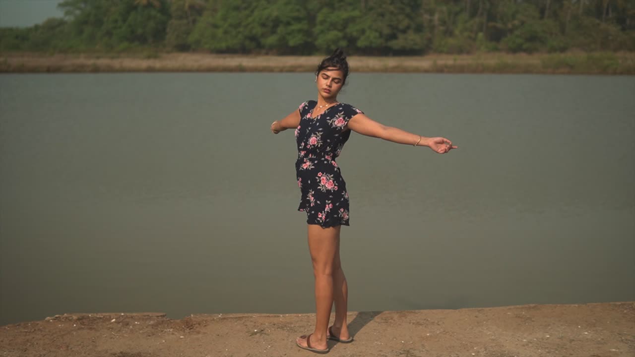 toma amplia de una mujer joven agitando sus manos alrededor en un lindo mono azul y rosa