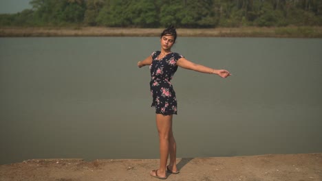 wide shot of a young woman waving her hands around in a cute blue and pink jumpsuit