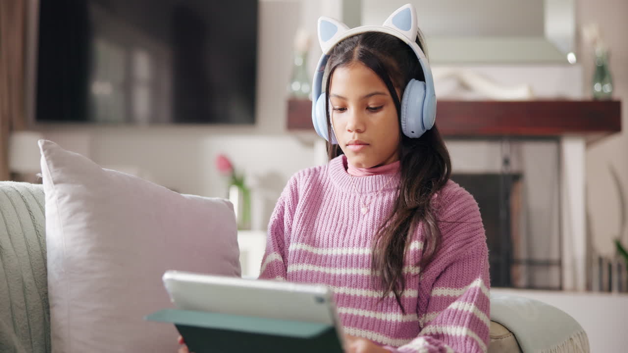 Girl using tablet with cat ear headphones at home