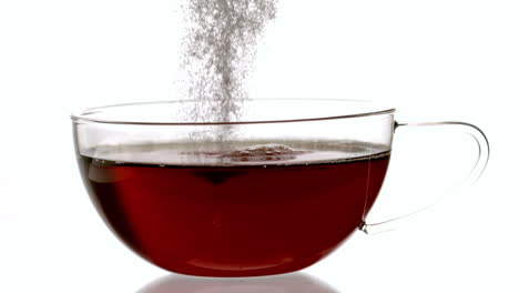 teaspoon pouring sugar into cup of tea